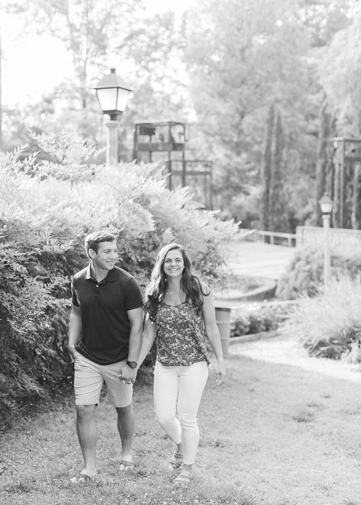 Chelsea Renay photographs engaged couple walking through Raleigh Rose Garden