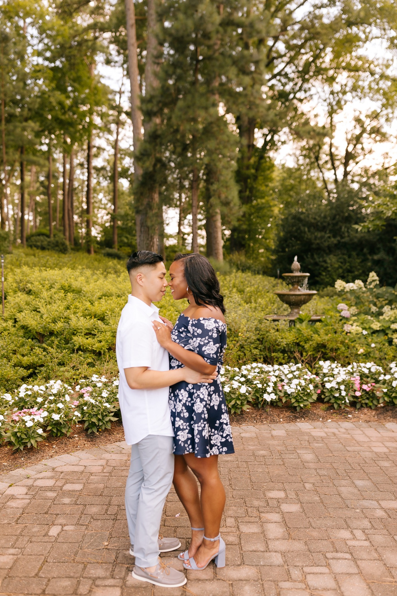 couple poses by fountain in WRAL Gardens
