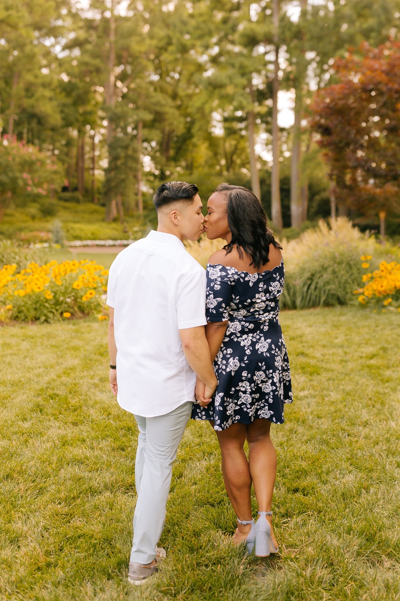 couple kisses while walking through WRAL Gardens