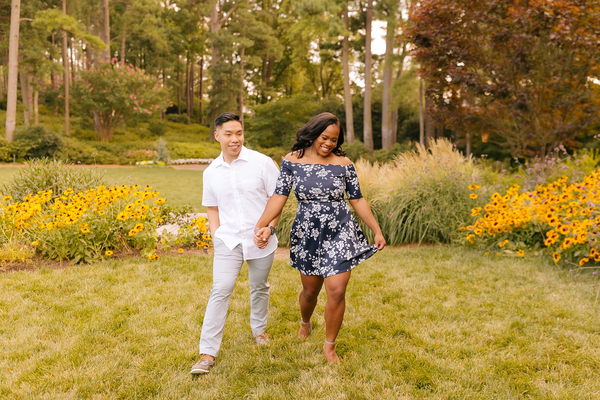 bride and groom walk through gardens laughing