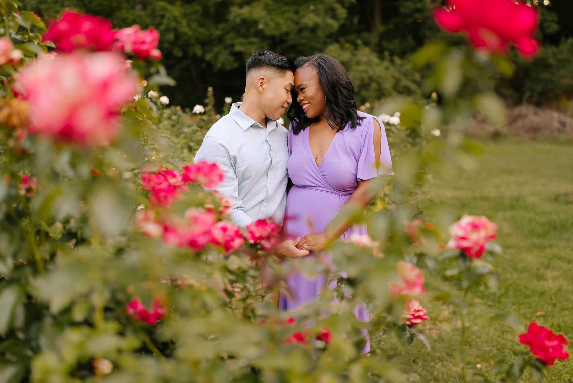 bride and groom touch foreheads during engagement session in WRAL Gardens