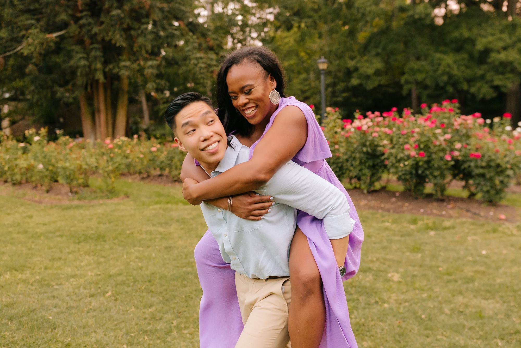 bride ride on groom's back during engagement session at Raleigh Rose Garden