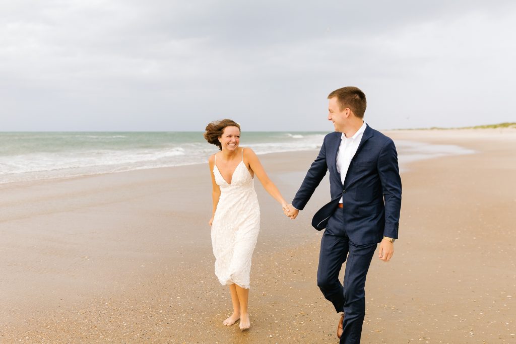 bride and groom hold hands walking in Outer Banks