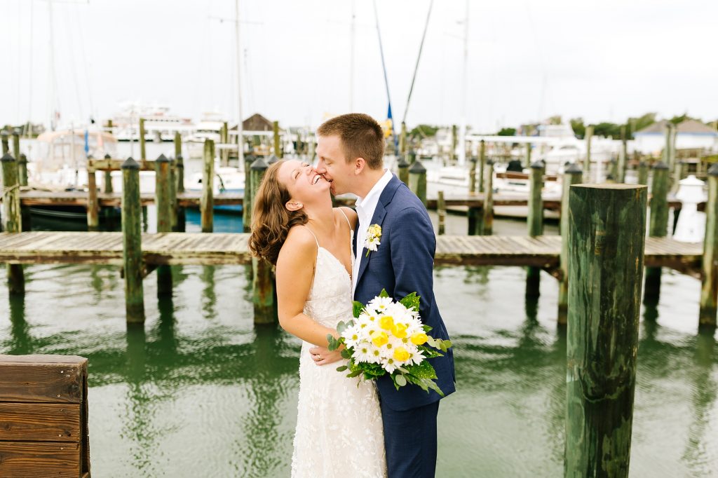 groom kisses bride while she tilts head back on docks