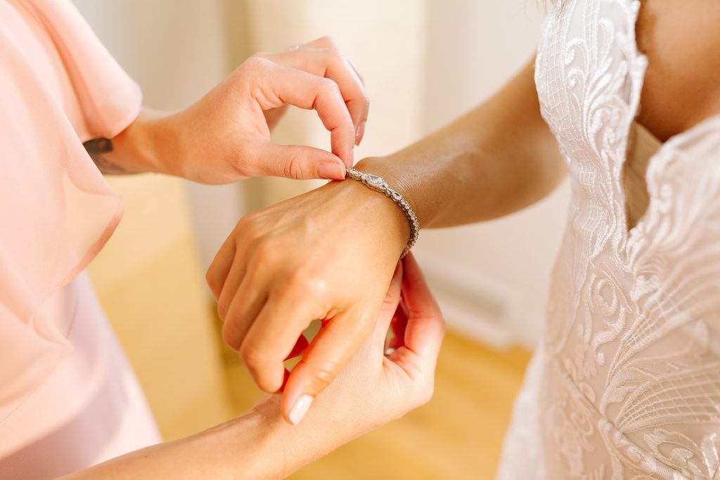 bridesmaid adjusts bride's bracelet