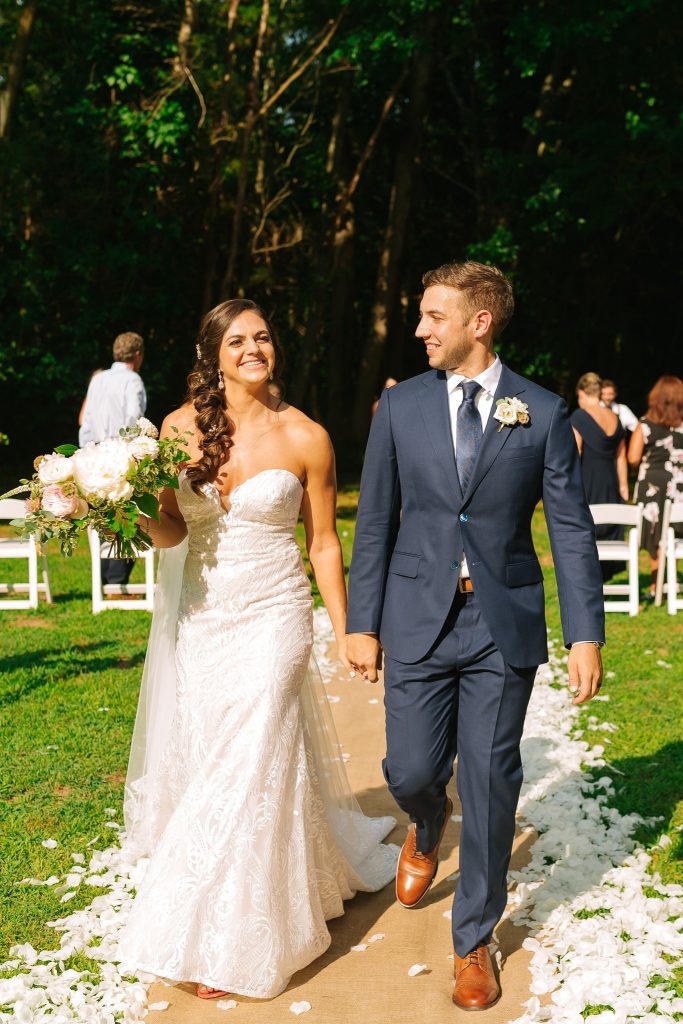 newlyweds walk up aisle in backyard