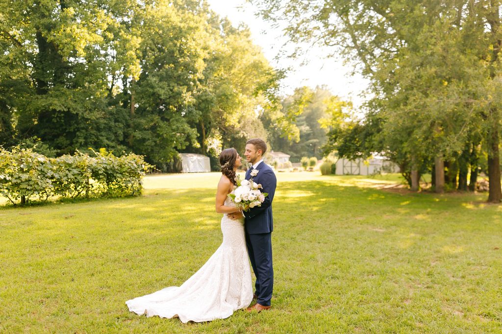 bride and groom pose in backyard with bouquet between them