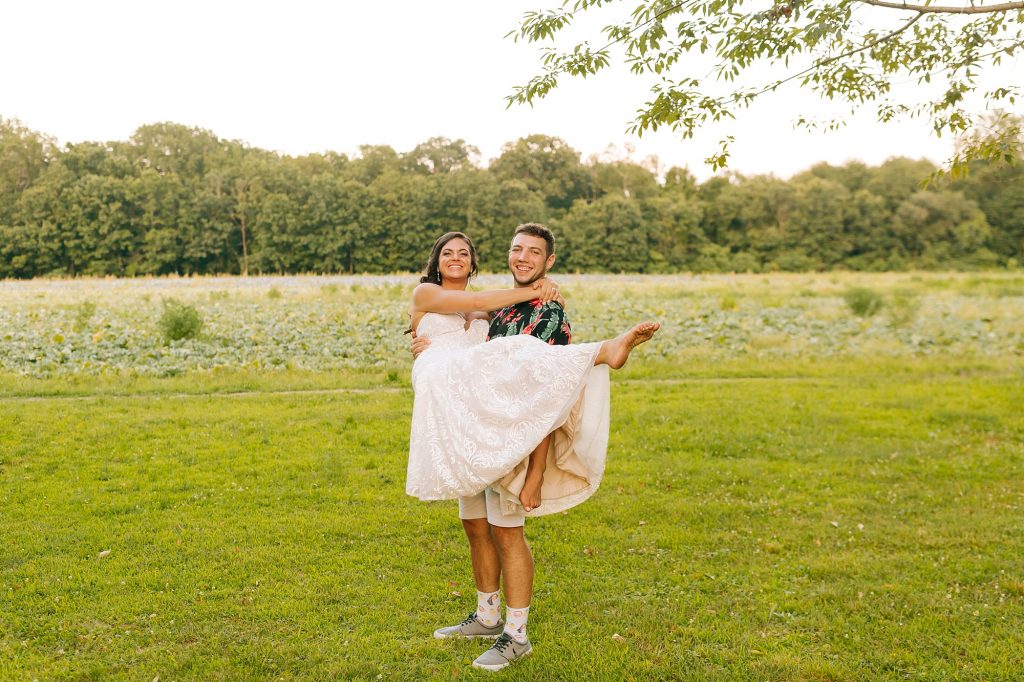 groom in Hawaiian shirt lifts barefoot bride