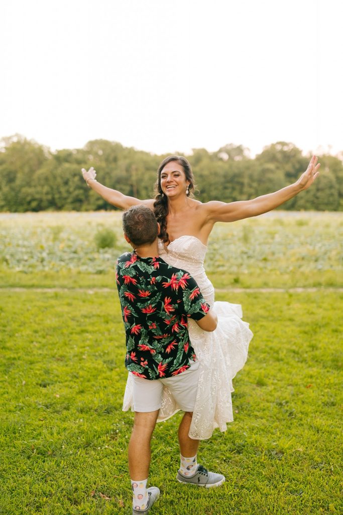 groom lifts bride with arms open during wedding photos