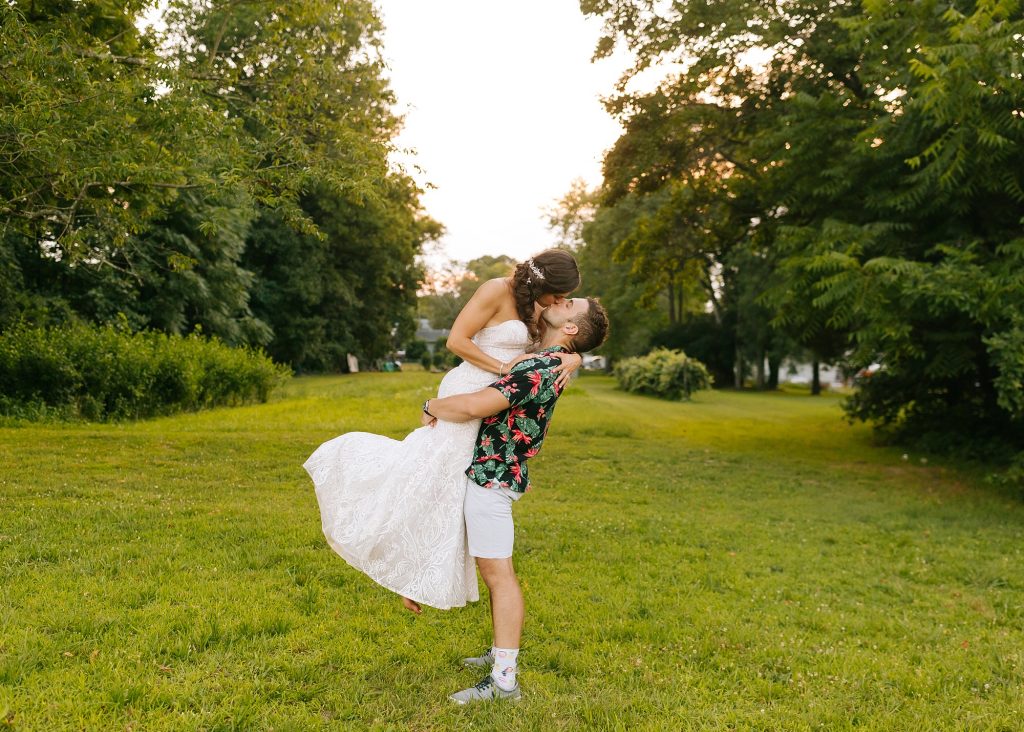 bride kisses groom while being lifted off the ground