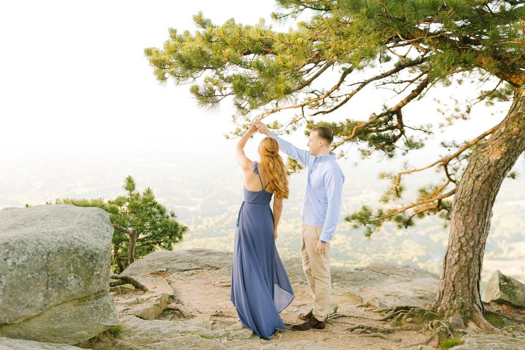 groom twirls bride in blue gown on Pilot Mountain
