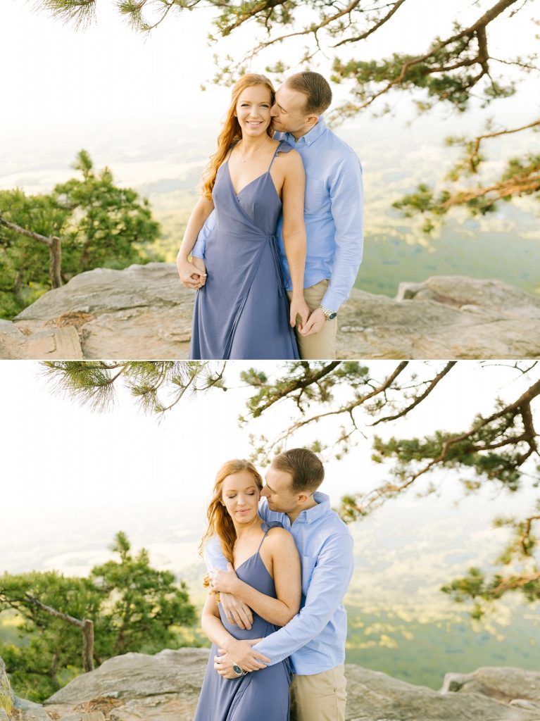 groom hugs bride from behind on Pilot Mountain during engagement photos