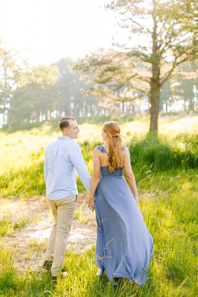 engaged couple holds hands and walks on mountaintop