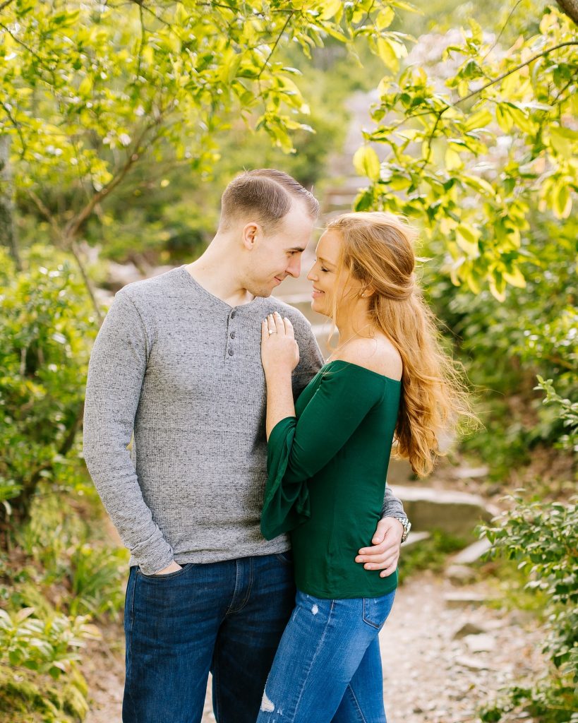 bride and groom pose in jeans in long sleeve shirts on Pilot Mountain