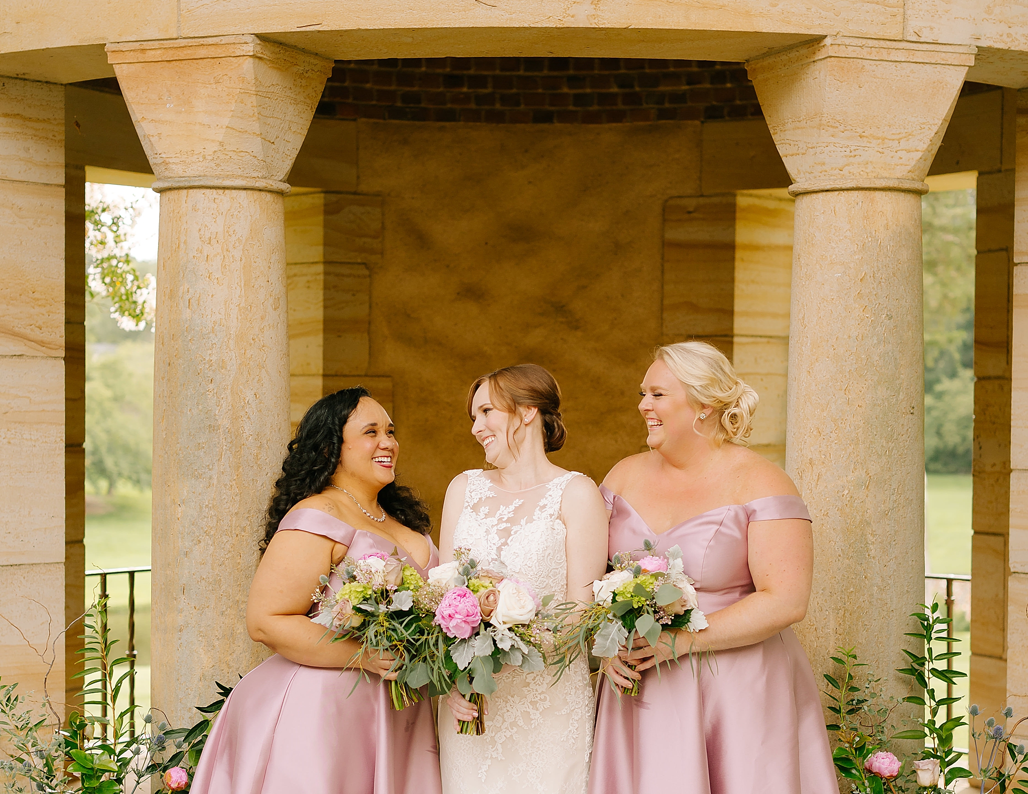 bride laughs with bridesmaids in pink satin bridesmaid gowns