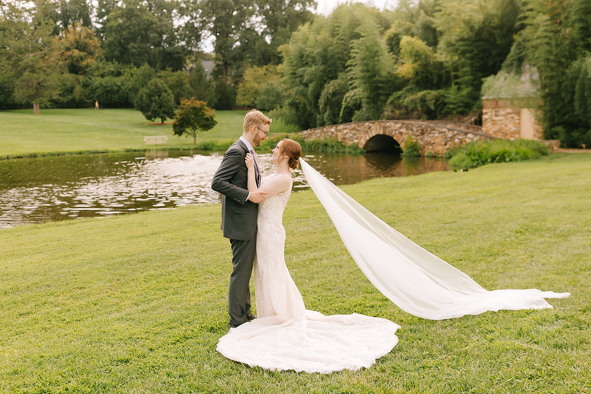 bride and groom pose by lake at Graylyn Estate