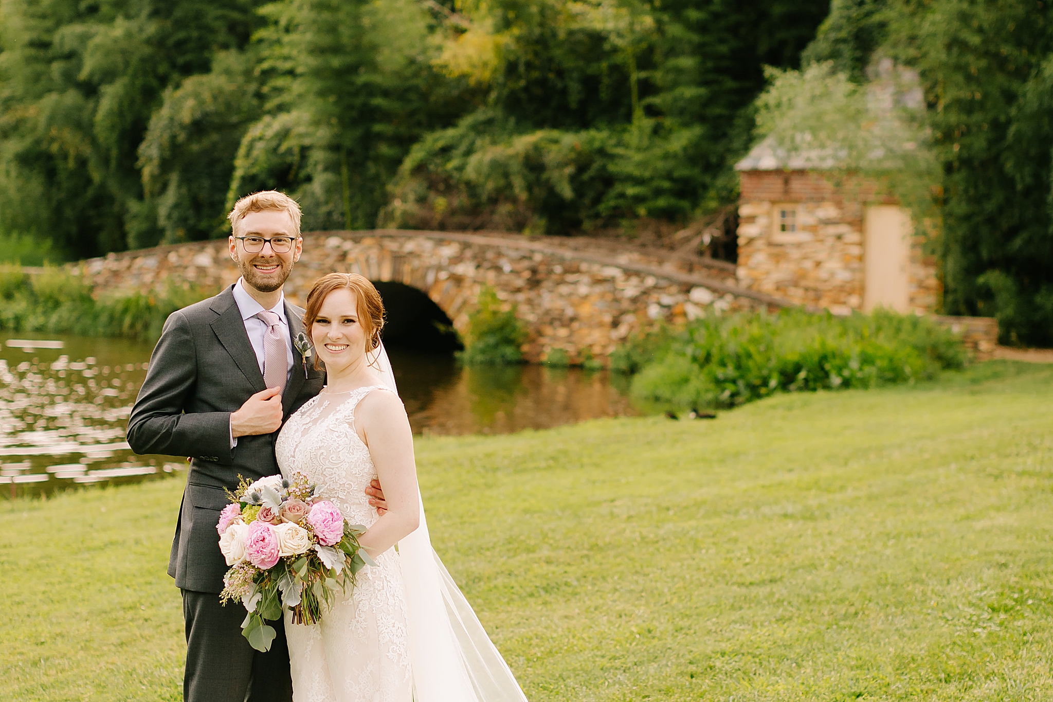 newlyweds stand together in front of bridge at Graylyn Estate