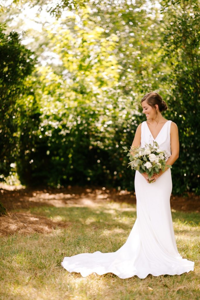 bride holds bouquet and looks over shoulder in modern wedding dress