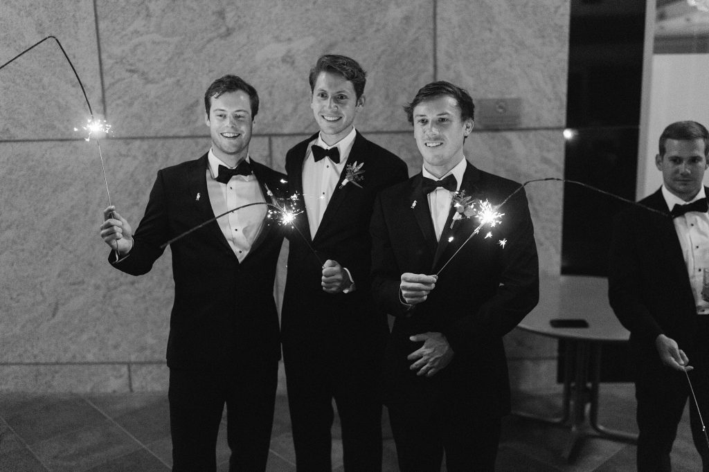 groomsmen hold sparklers during wedding exit