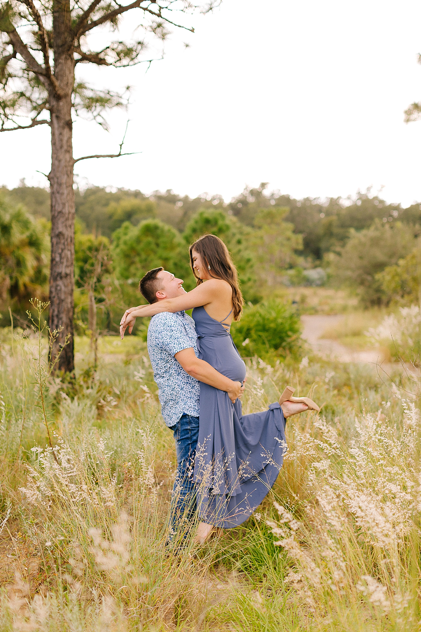 engaged couple laugh while standing in tall grass at Bok Tower