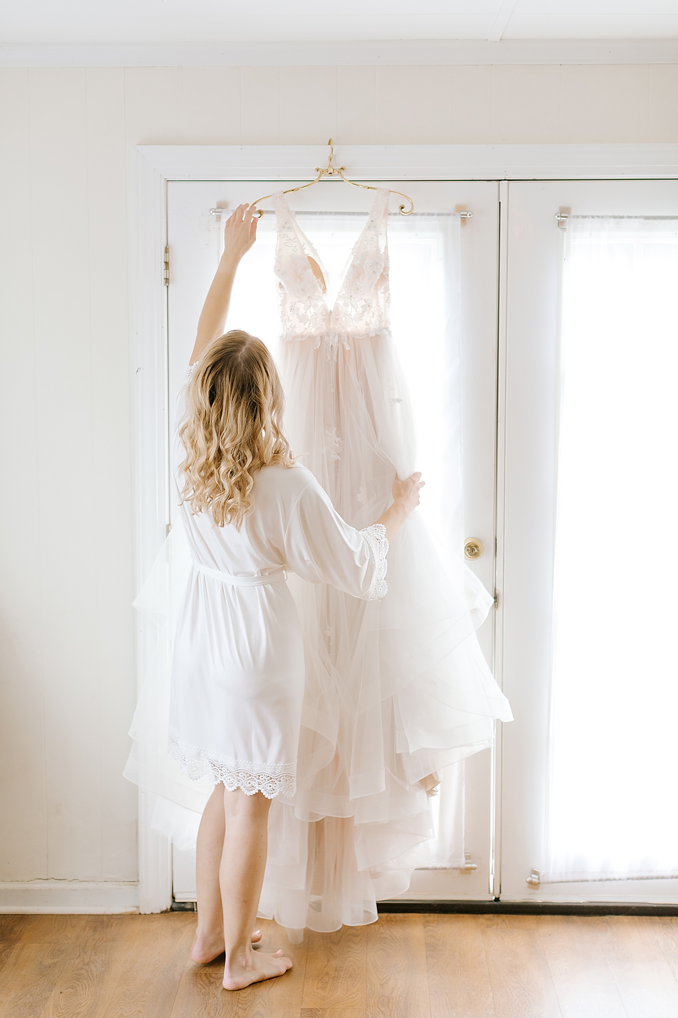 bride hangs dress in window before getting ready