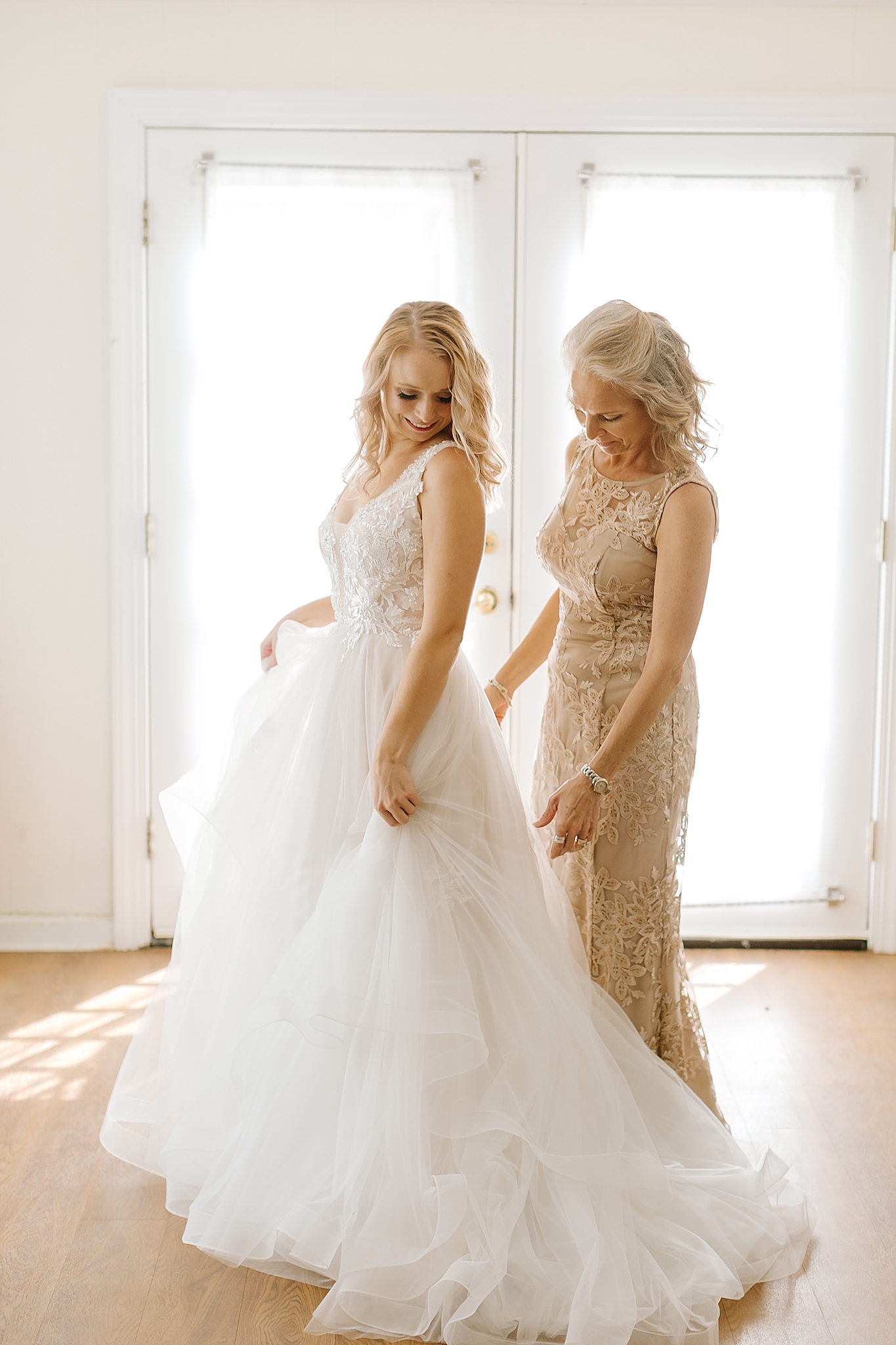 mom adjusts bride's gown during morning prep
