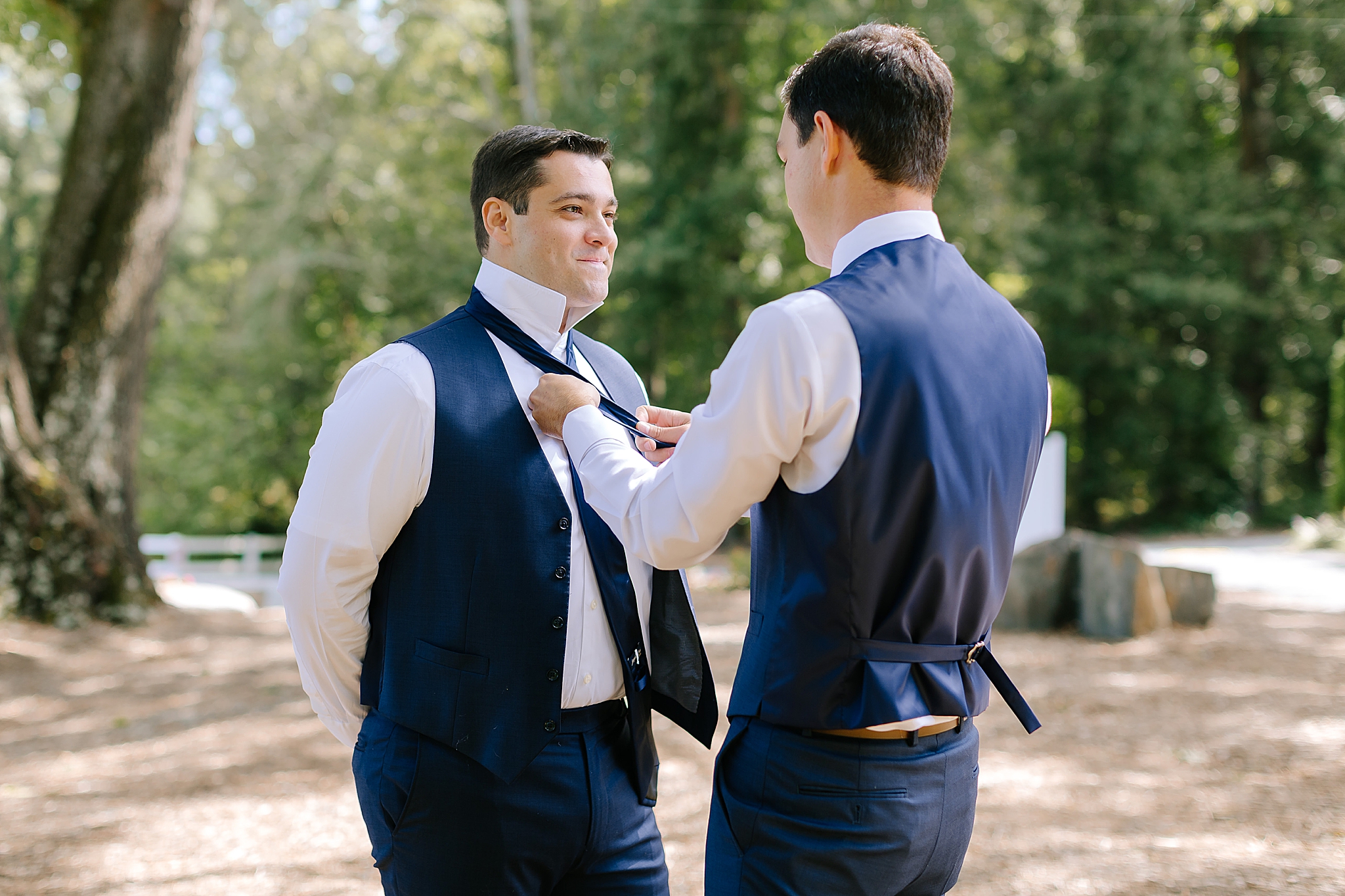 groomsman adjusts tie for groom before Camellia Gardens wedding