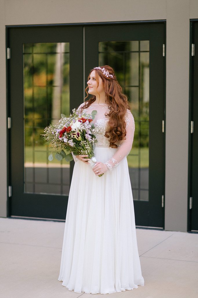 bride holds bouquet of red and white flowers