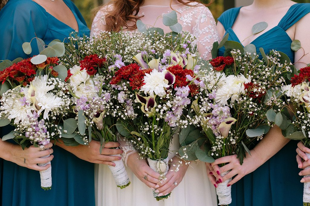 bridesmaids in jewel toned wedding dresses hold bouquets