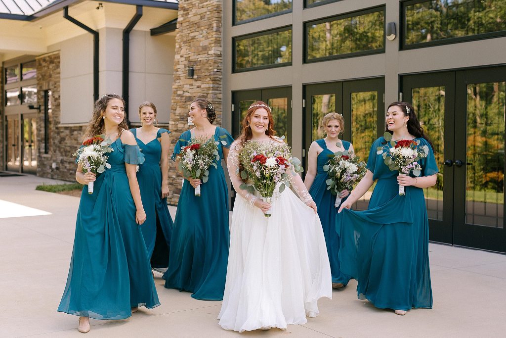 bride walks with bridesmaids in teal gowns
