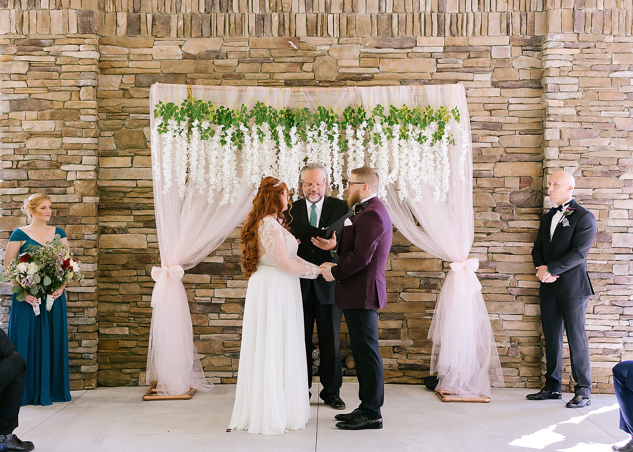 bride and groom exchange vows in front of floral ceremony decor