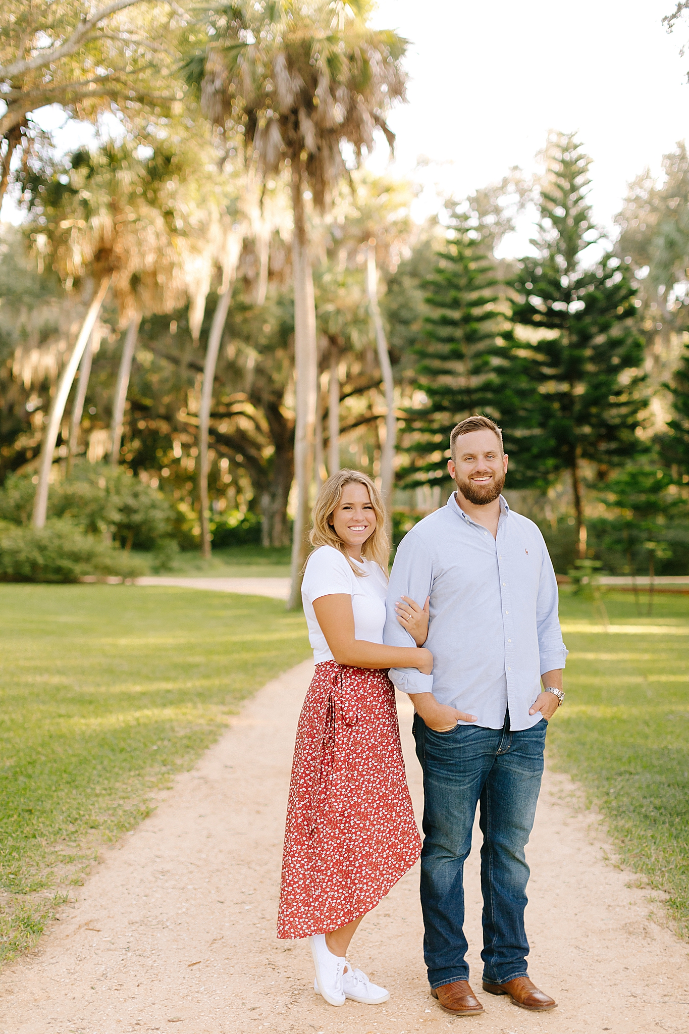 bride and groom pose by palm trees during sunset engagement session