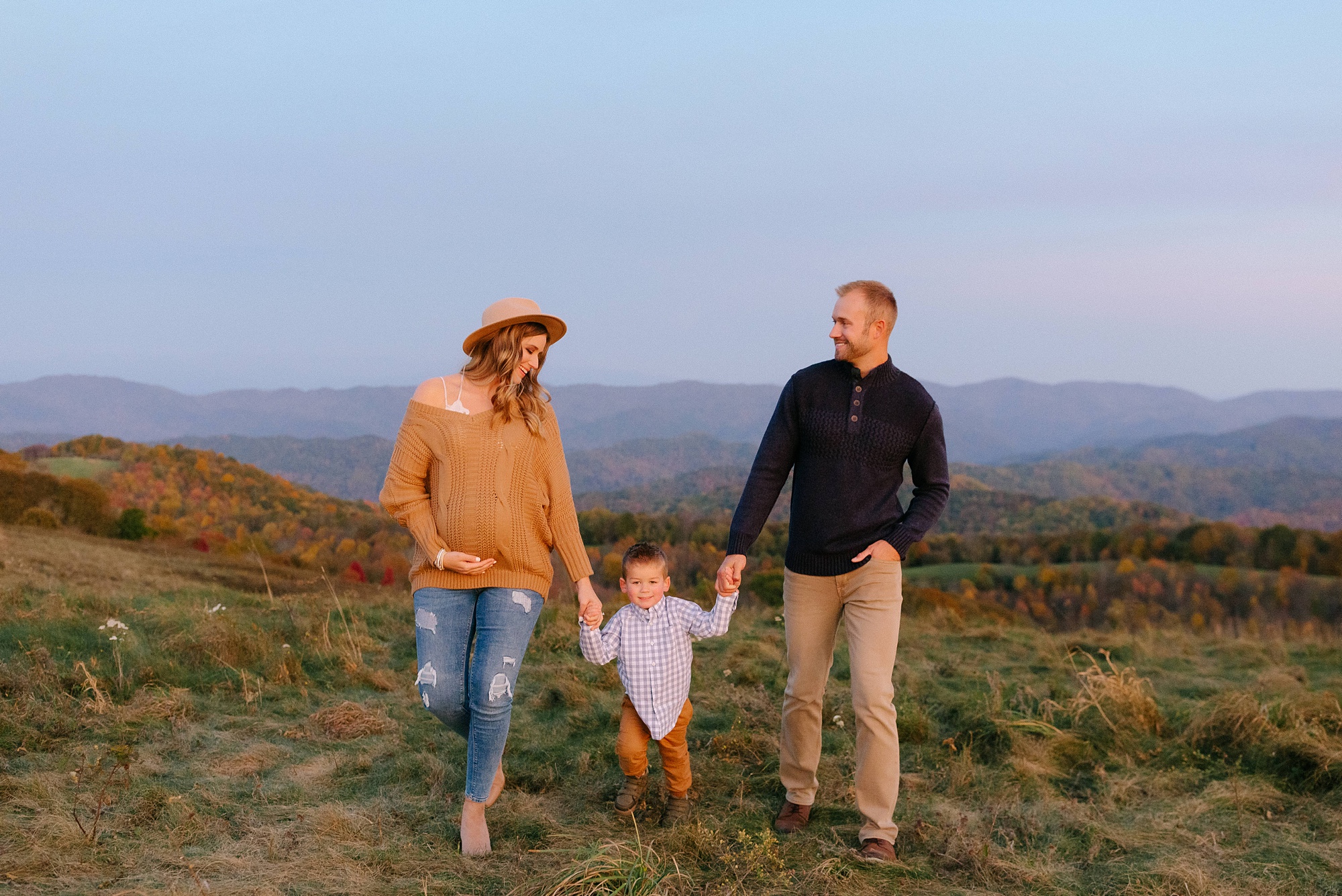 family of three walks at Max Patch during maternity session