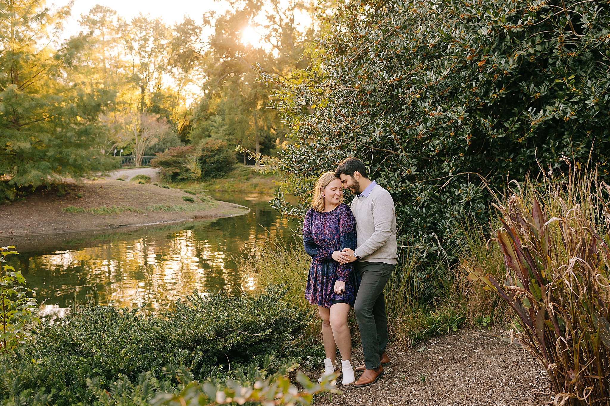 engaged couple poses by pond in Pullen Park