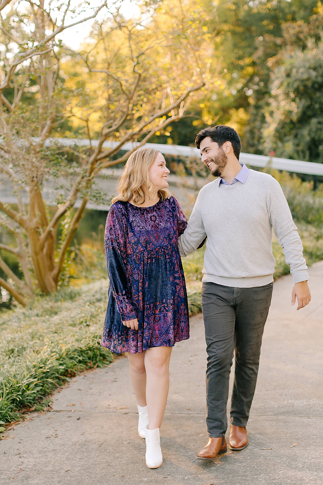 engaged couple walks through park during Pullen Park engagement session