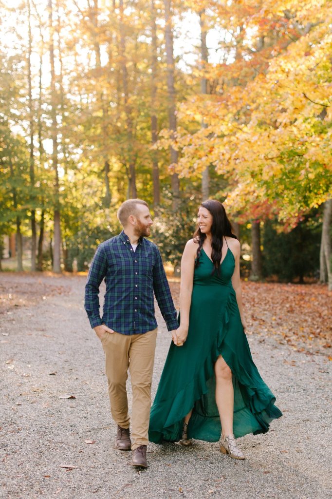 North Carolina couple walks through leaves at Greensboro Botanical Gardens