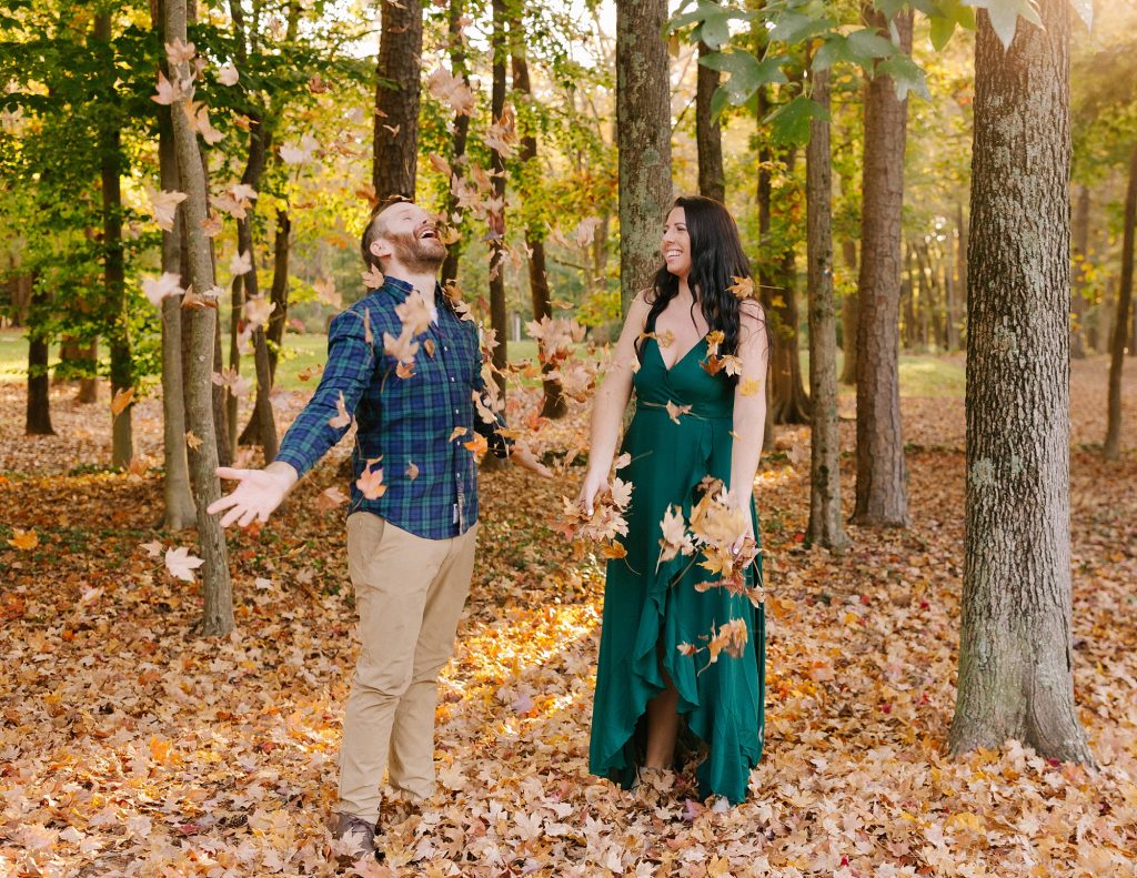 married couple throws leaves during fall anniversary portraits