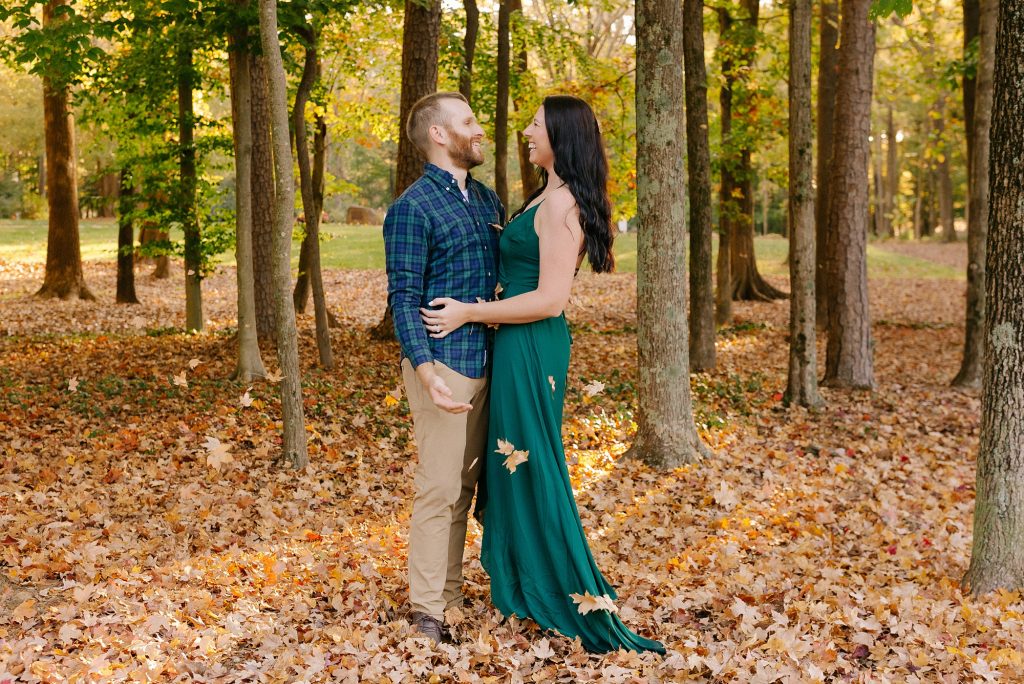 married couple throws leaves during fall anniversary portraits