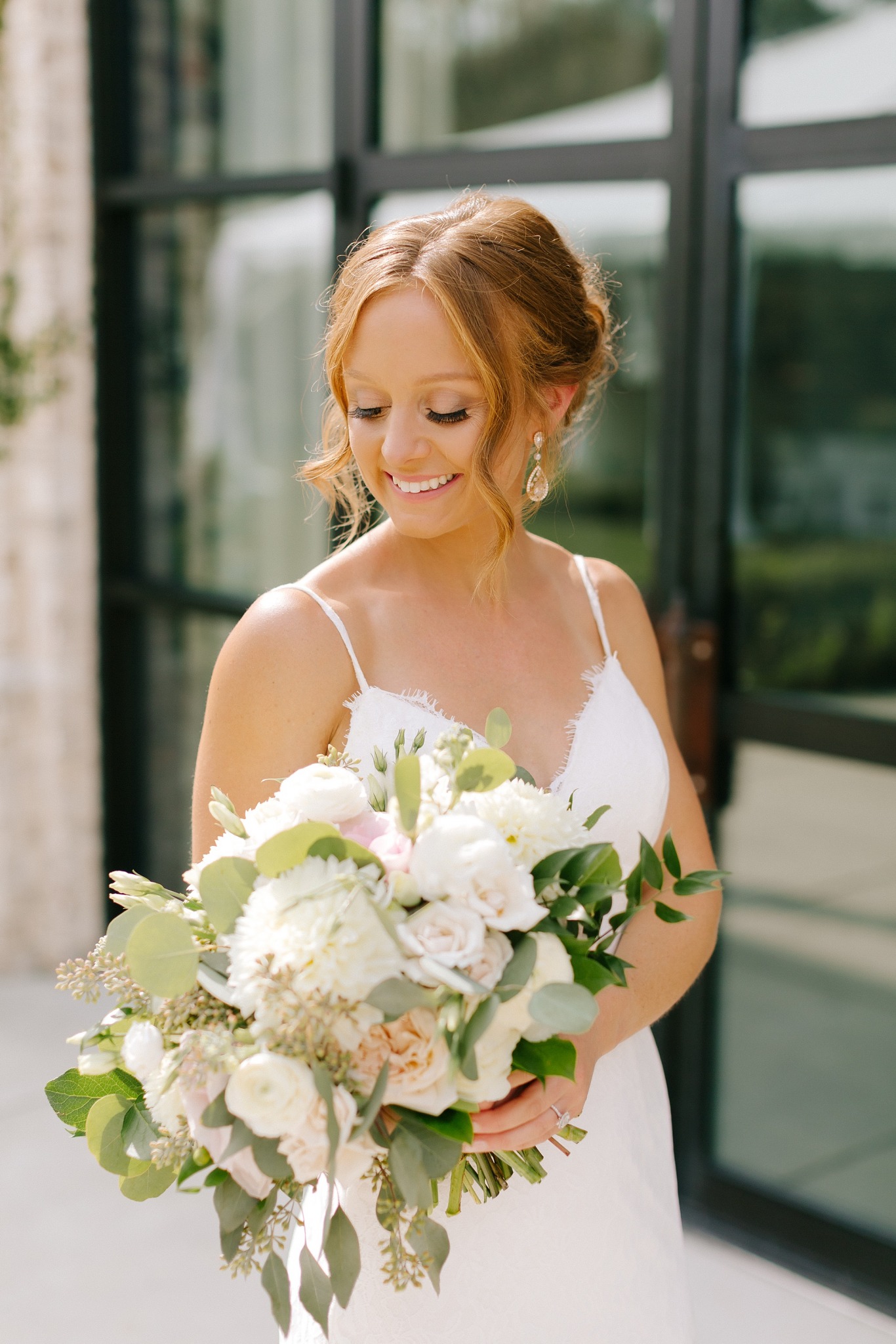 bride looks at bouquet during portraits outside Wrightsville Manor