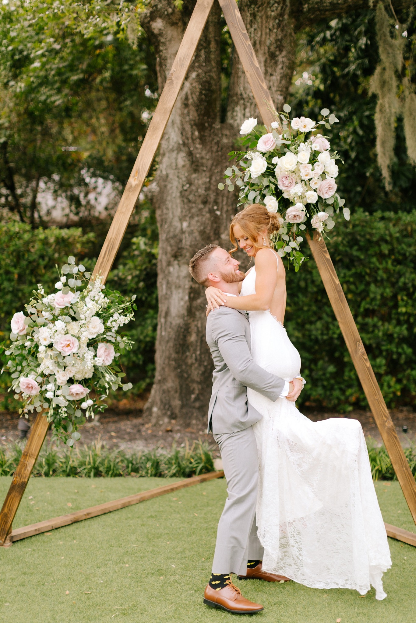 groom lifts bride during NC wedding portraits in gardens of Wrightsville Manor