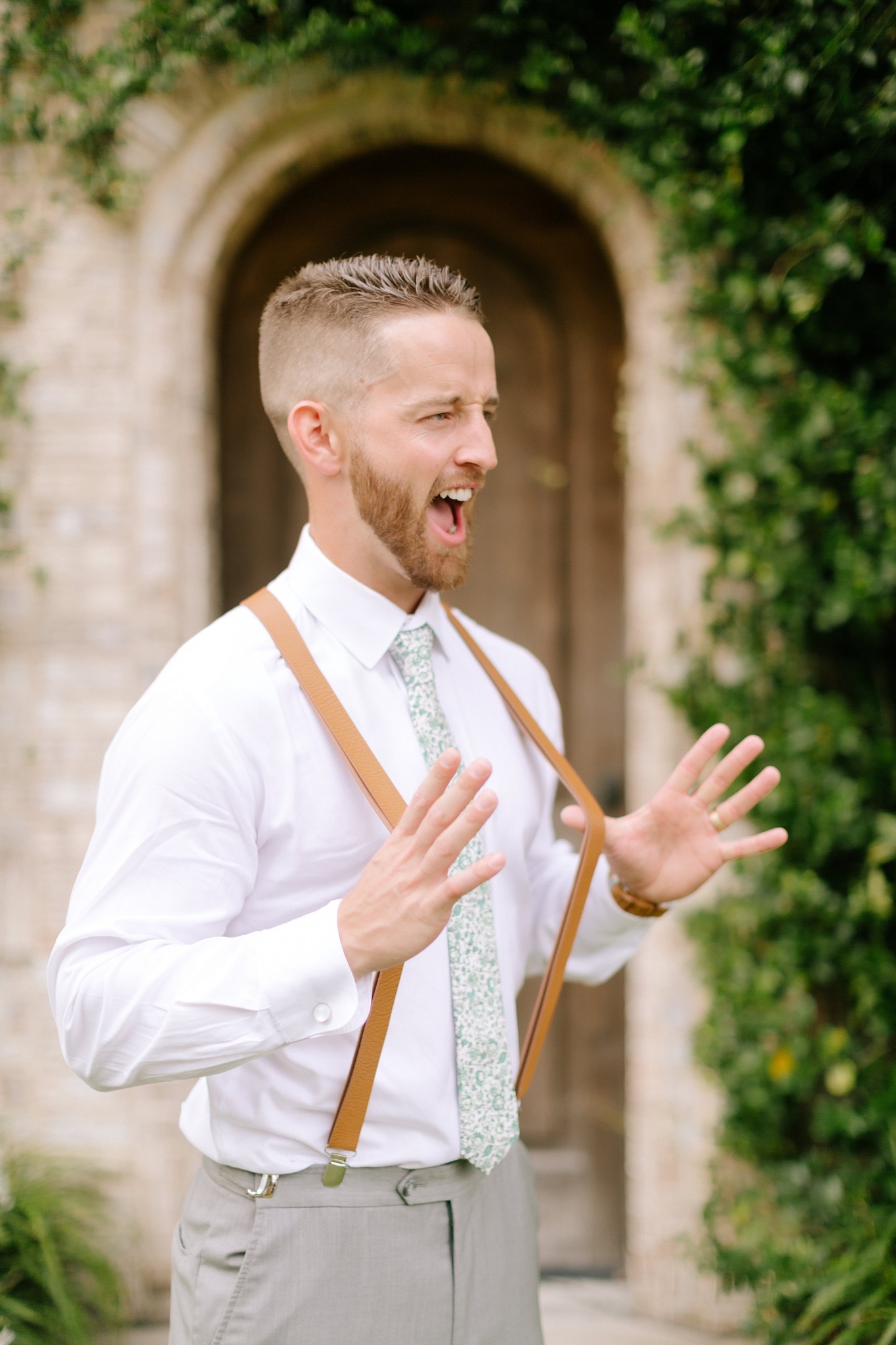 groom pulls suspenders during wedding photos