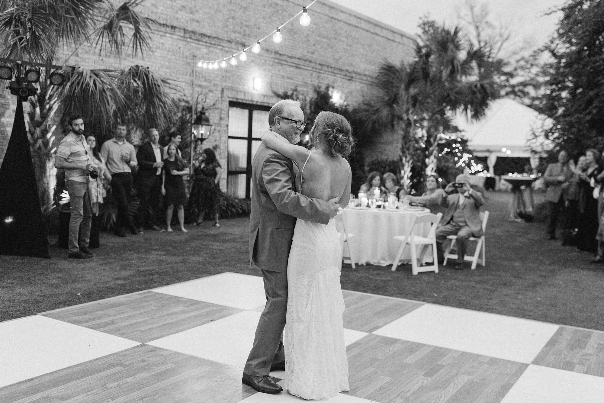 bride and dad dance on checkered dance floor during garden wedding reception