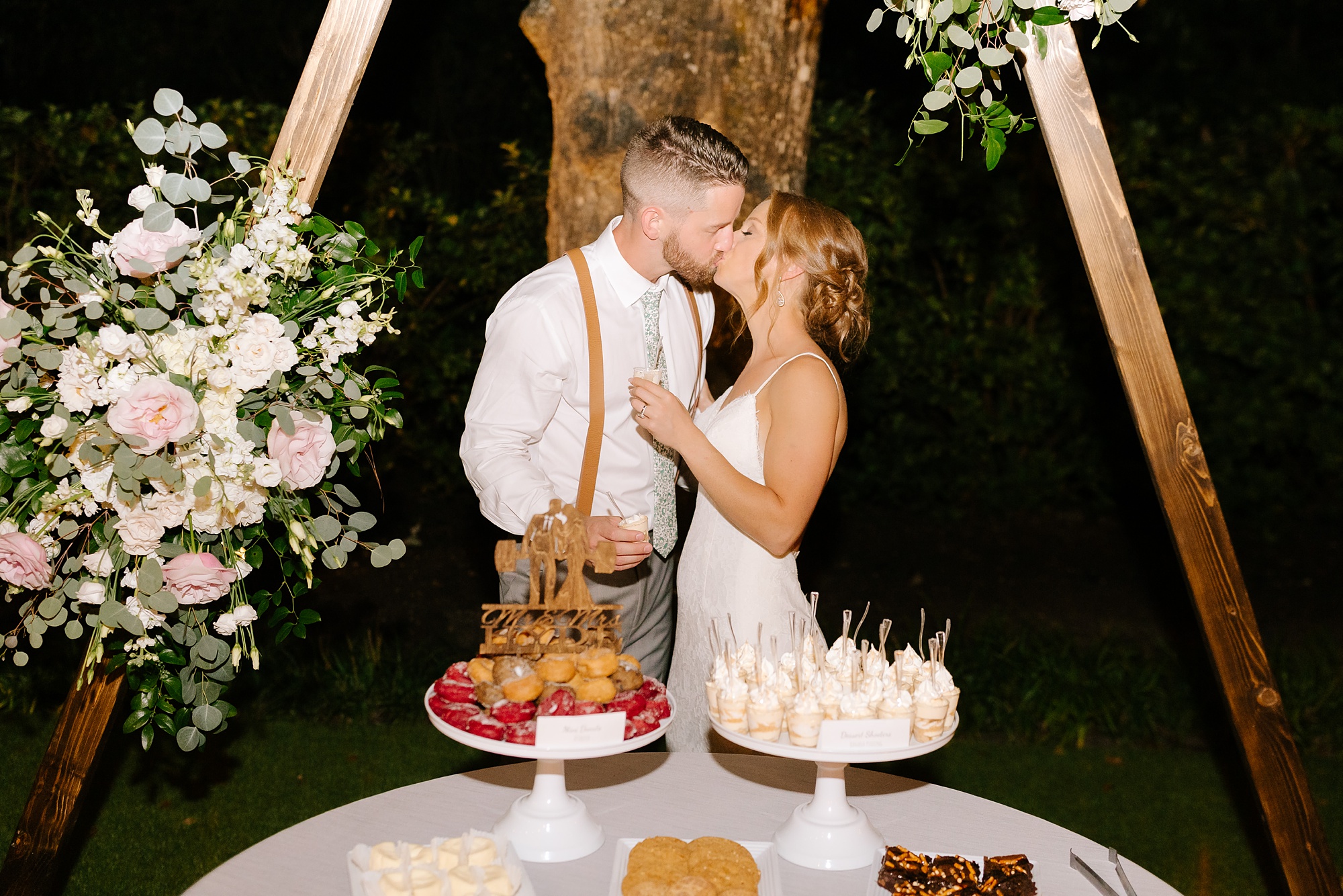 newlyweds kiss by cake table during Wilmington NC wedding reception