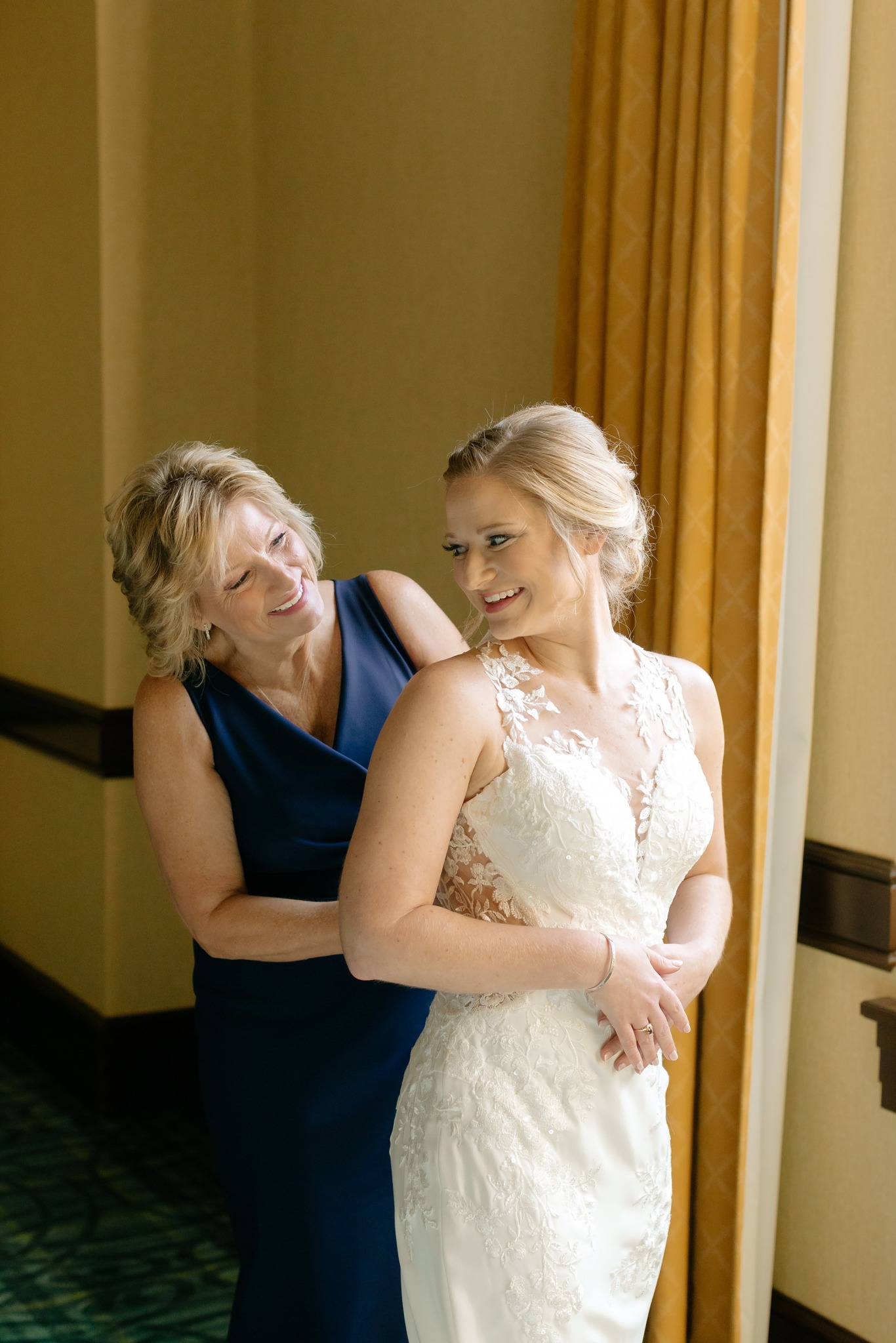 mother adjusts bride's dress before first look