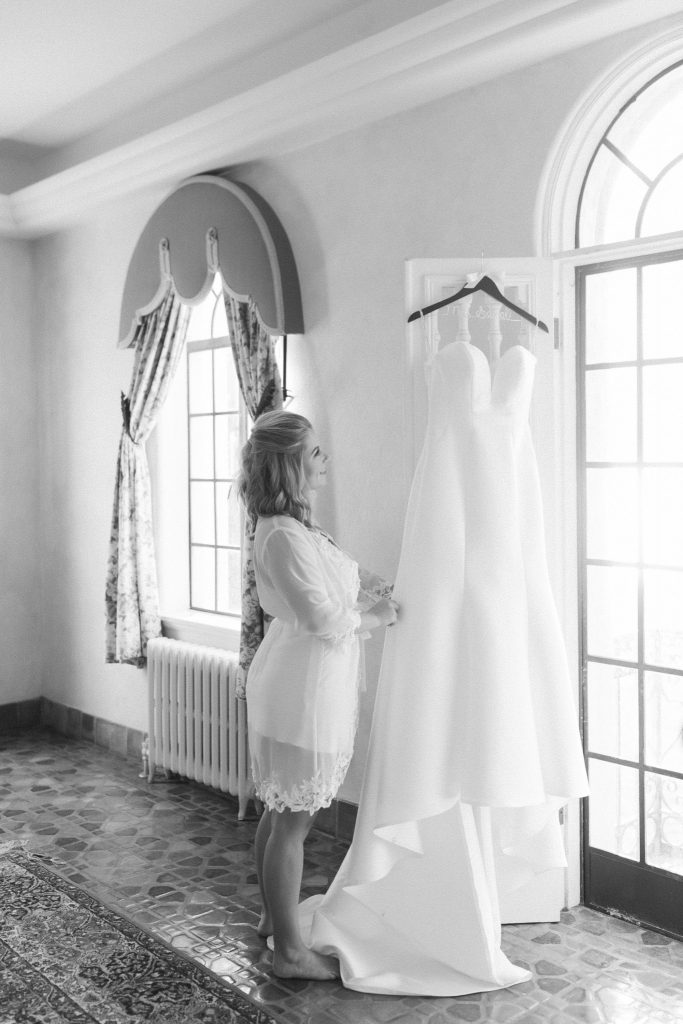bride looks at wedding dress hanging in Florida
