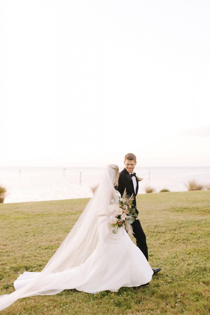 bride and groom walk along waterfront in Sarasota FL