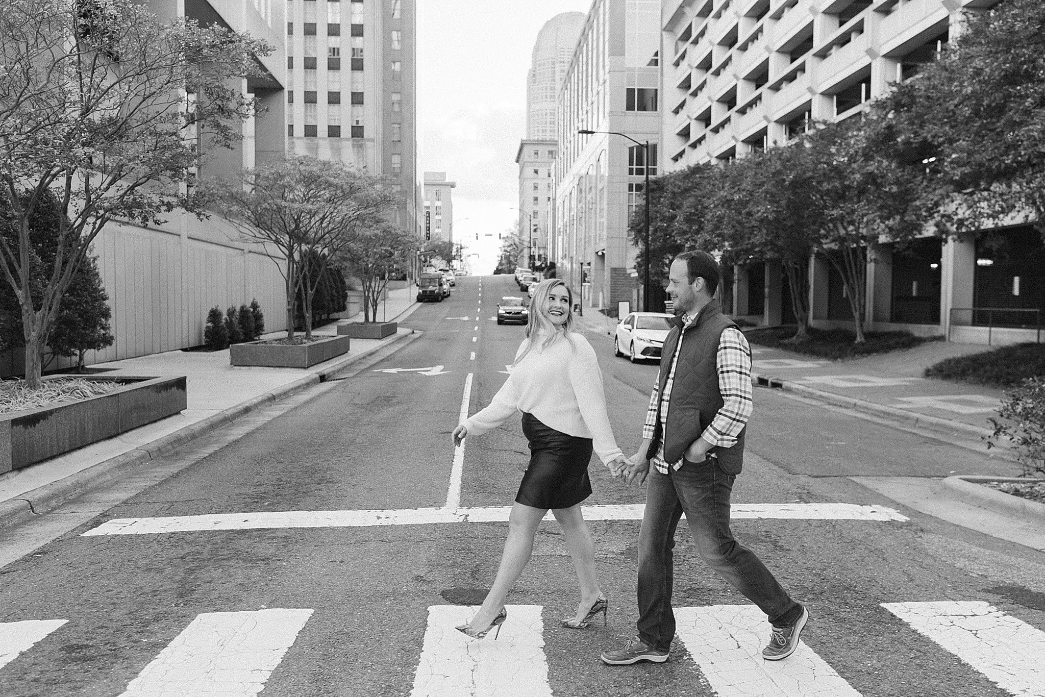 married couple holds hands walking through crosswalk in Downtown Winston-Salem