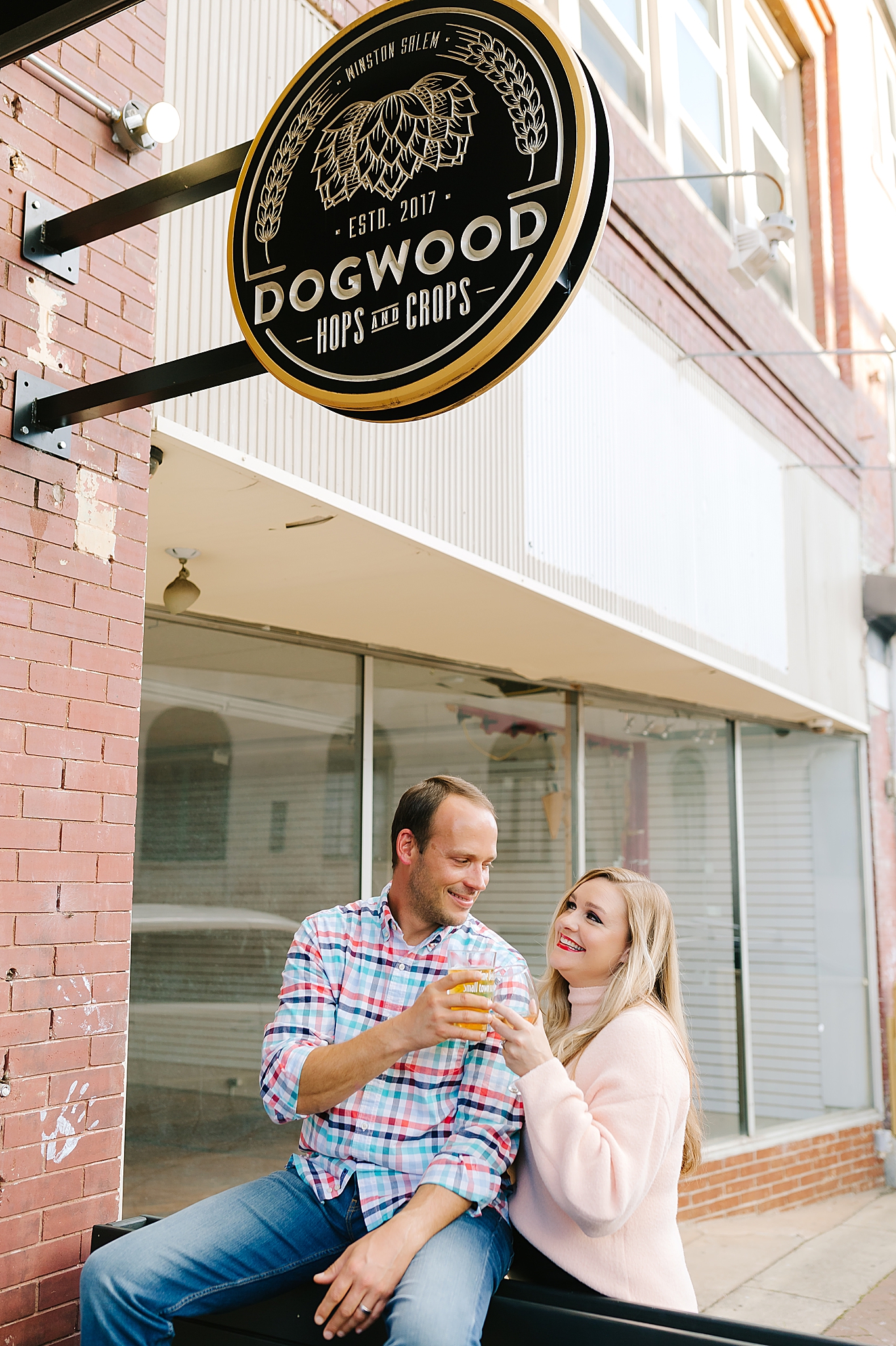 married couple toasts with beers in downtown winston NC