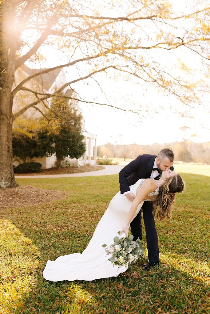 groom kisses bride while dipping her at The Meadows Raleigh