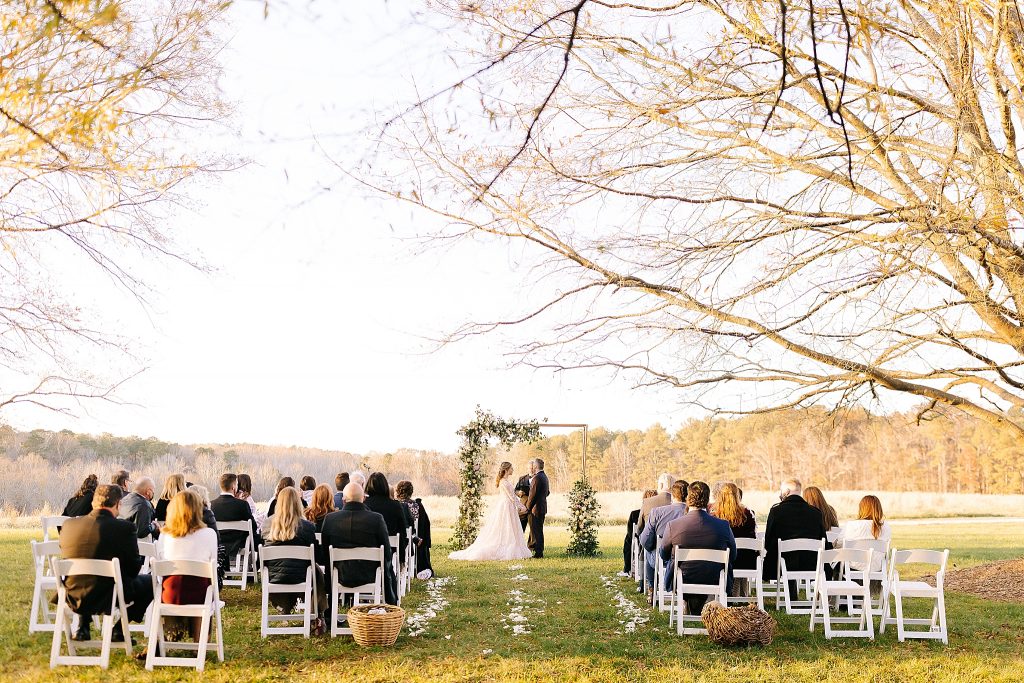 The Meadows Raleigh wedding ceremony outside under modern gold arbor